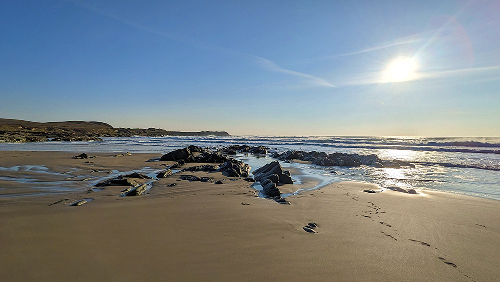 Picture of a sandy beach with a few rocks on a sunny April afternoon
