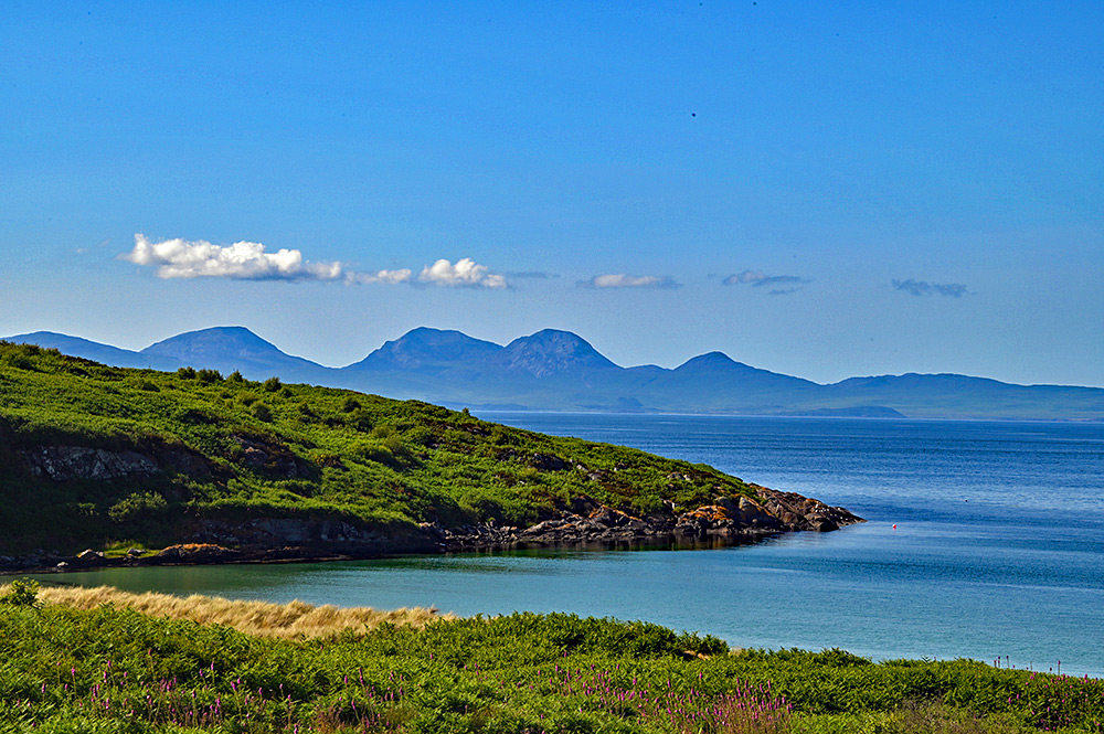 Picture of a coastal landscape on an island, another island with some mountains in the background