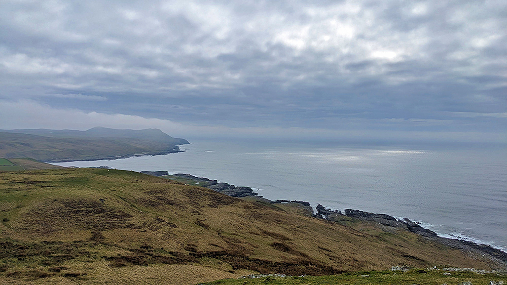 Picture of a cloudy moody view along a rocky shoreline from the top of a hill