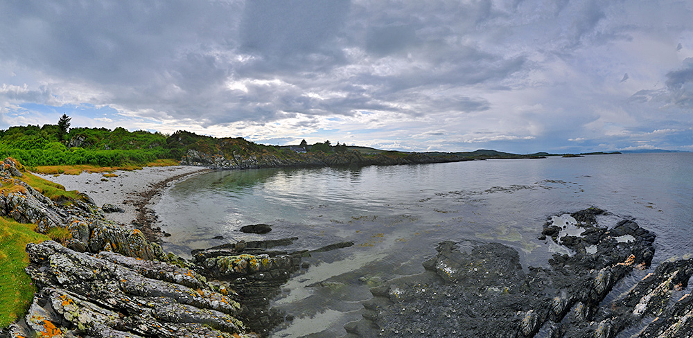 Panoramic picture of a small beach at the end of a rocky shoreline