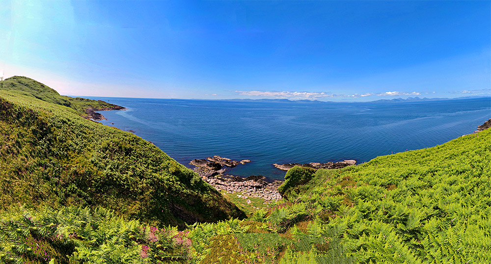 Panoramic picture of a coastal view from an island coastal walk, two other islands visible on the horizon across the sea
