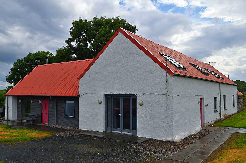 Picture of a holiday cottage building with a red corrugated iron roof after a heavy rain shower