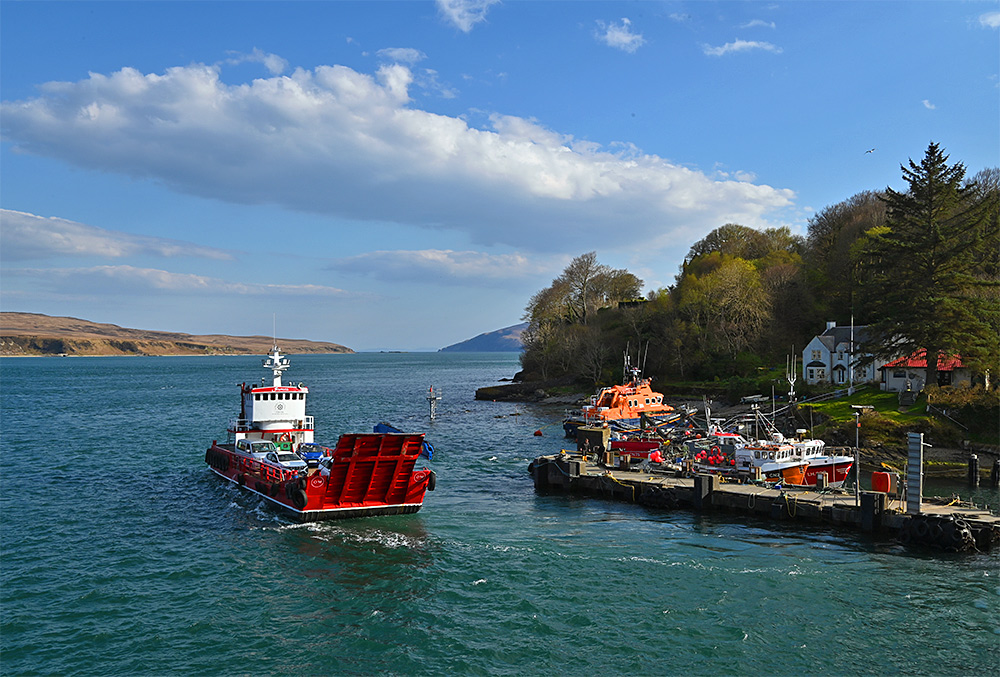 Picture of a small red ferry off a small port in a sound between two islands