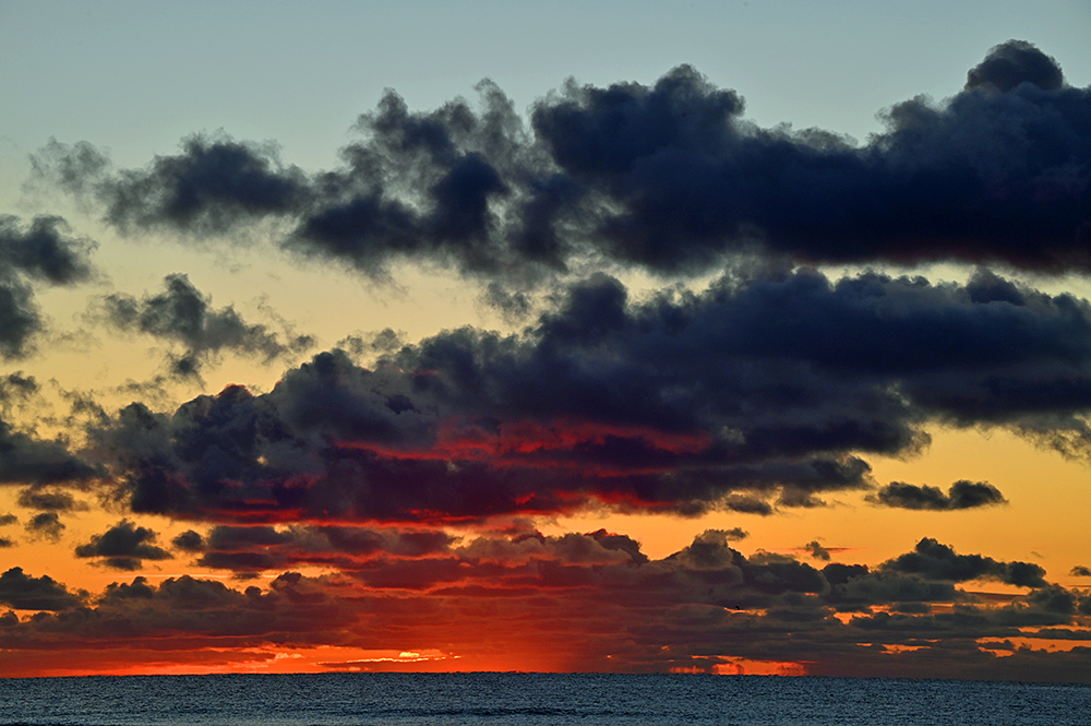 Picture of colourful red and orange clouds over a bay during a sunset