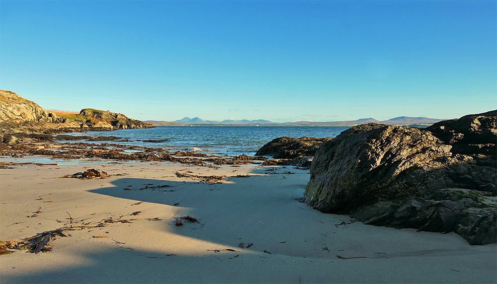 Picture of a small beach with some rocks on the side in winter sunshine