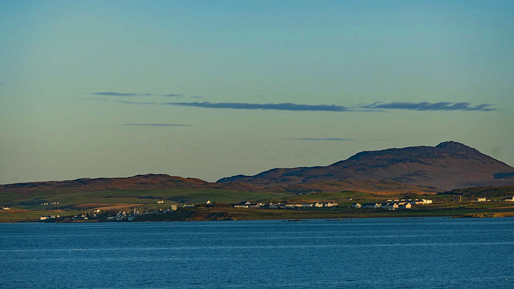 Picture of a coastal village in the November afternoon sunshine, seen across a calm sea loch