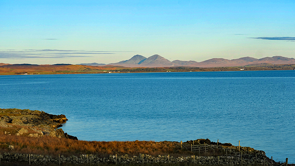 Picture of a view over a calm sea loch in November afternoon sunshine, mountains in the distance