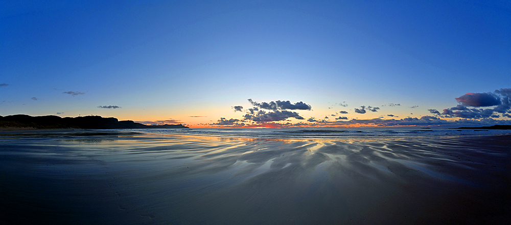 Picture of a panoramic view over a wide sandy beach in the gloaming