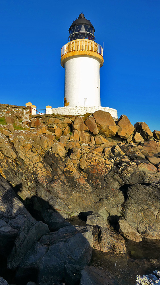 Picture of a small white lighthouse on top of a rocky shore