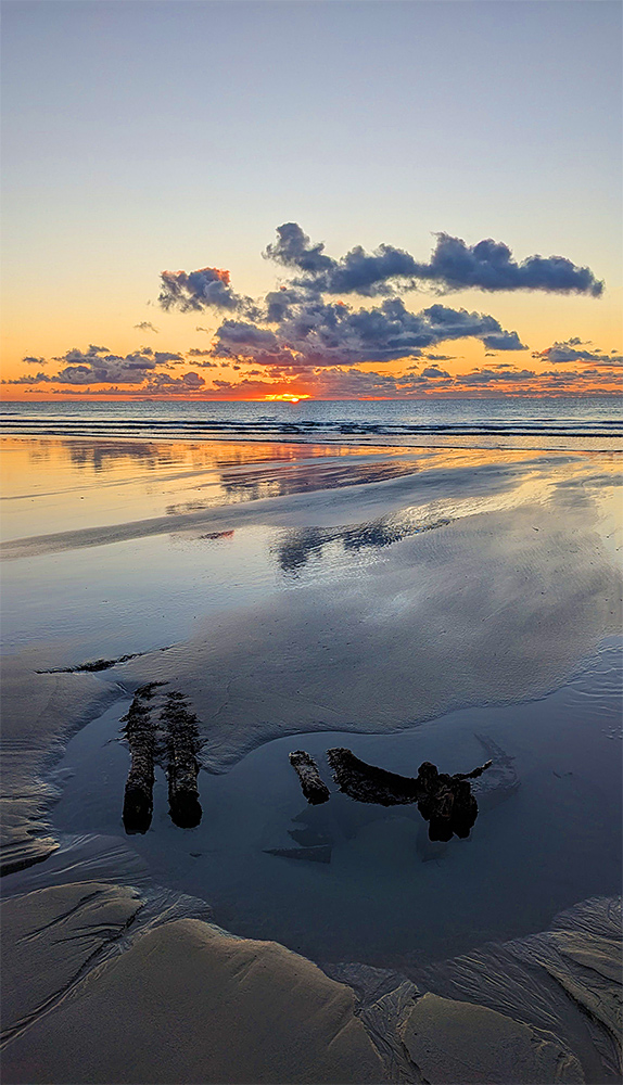 Picture of a wreck on a sandy beach during a sunset over the sea