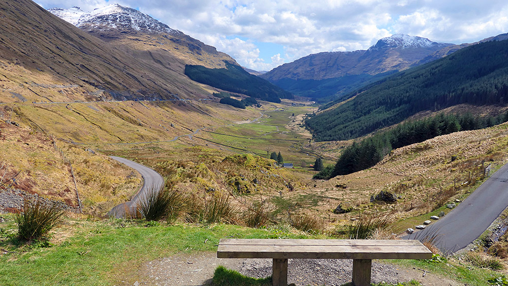 Picture of a wooden bench at the top of a mountain pass at the end of a valley