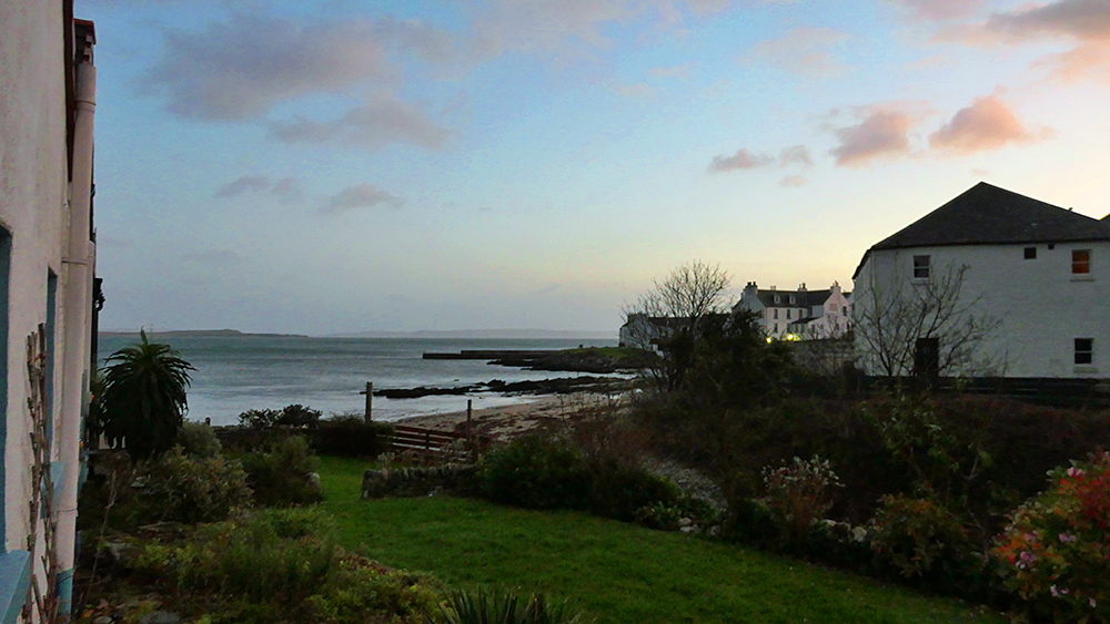 Picture of a view from the garden of a coastal cottage over a sea loch and a coastal village