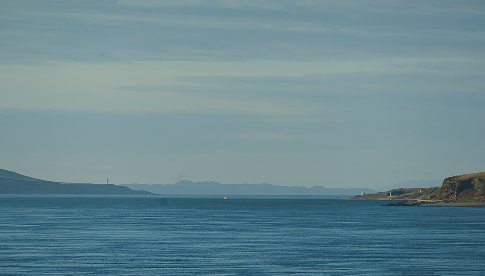 Picture of a view up a sound between two islands, a third island visible in the distance. Lighthouses on both sides. A small ferry crossing the channel