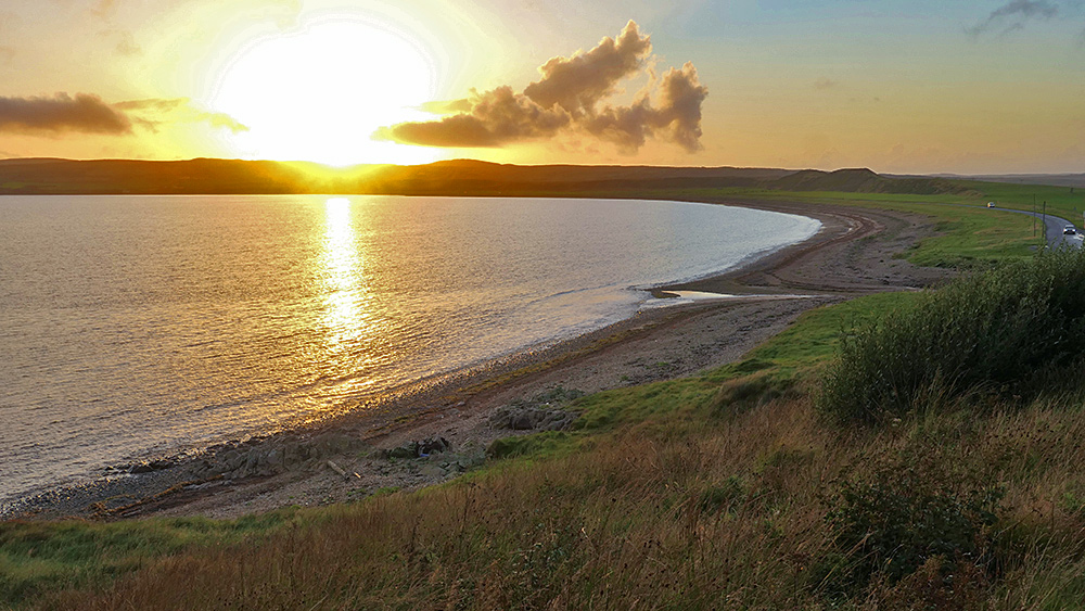 Picture of a sunset seen from the end of a beach in a sea loch