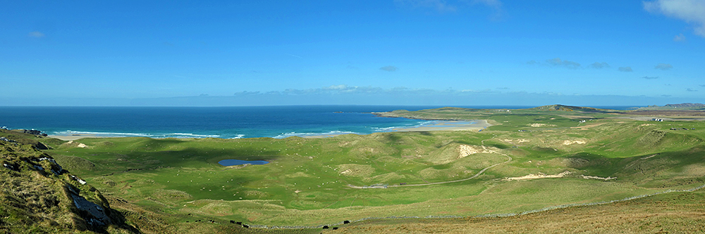 Panoramic picture of a view across some dunes to a wide bay