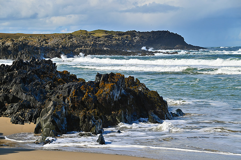 Picture of a rocky shore with some cliffs, waves rolling in from the Atlantic