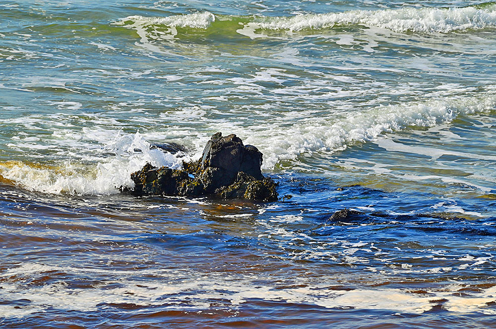 Picture of some small waves breaking in shallow water around a small rocky outcrop