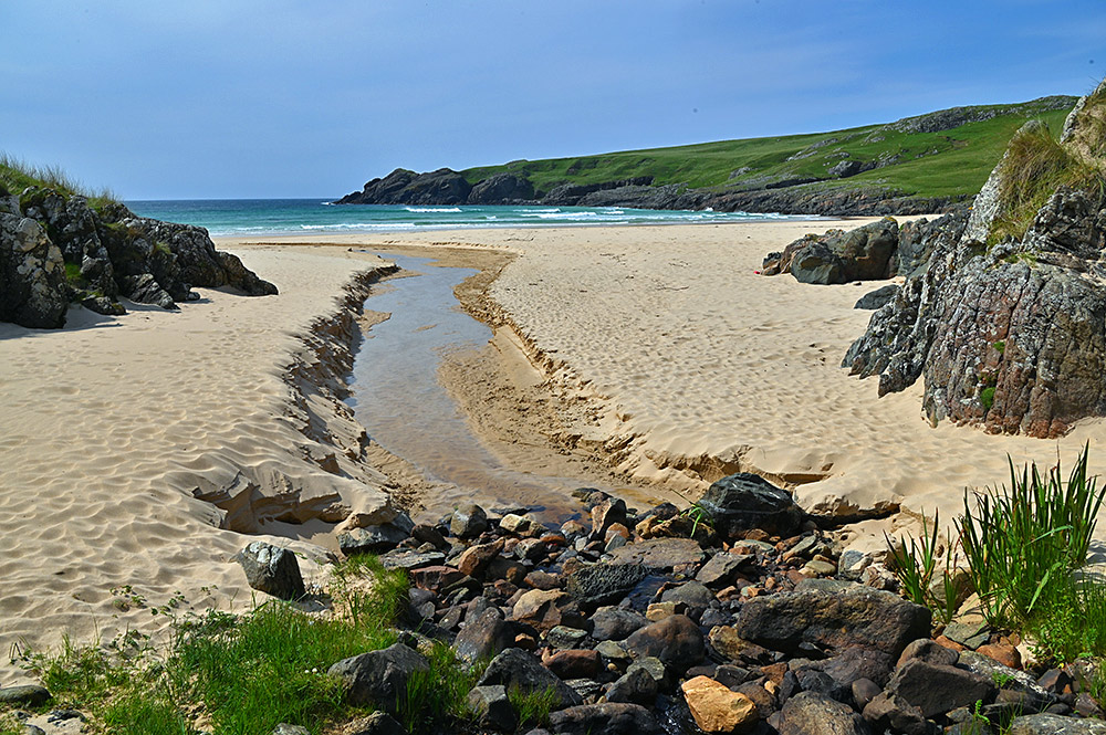 Picture of a small stream flowing through a sandy beach in a bay