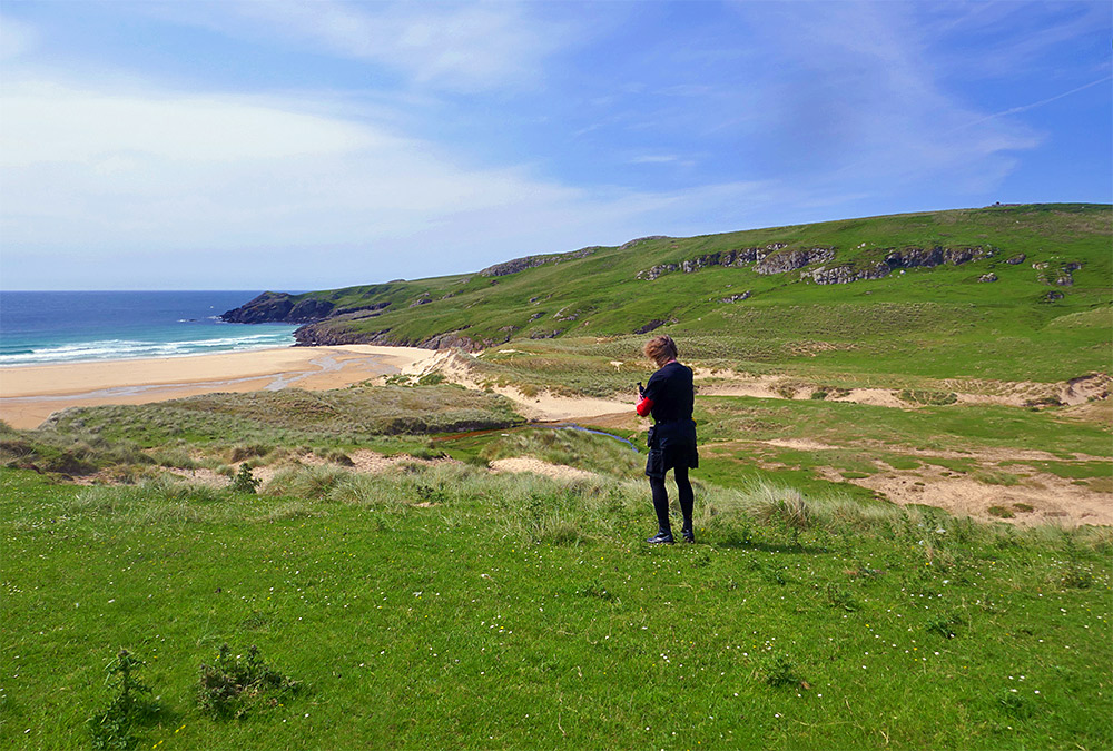 Picture of a person filming a video from the dunes above a beach