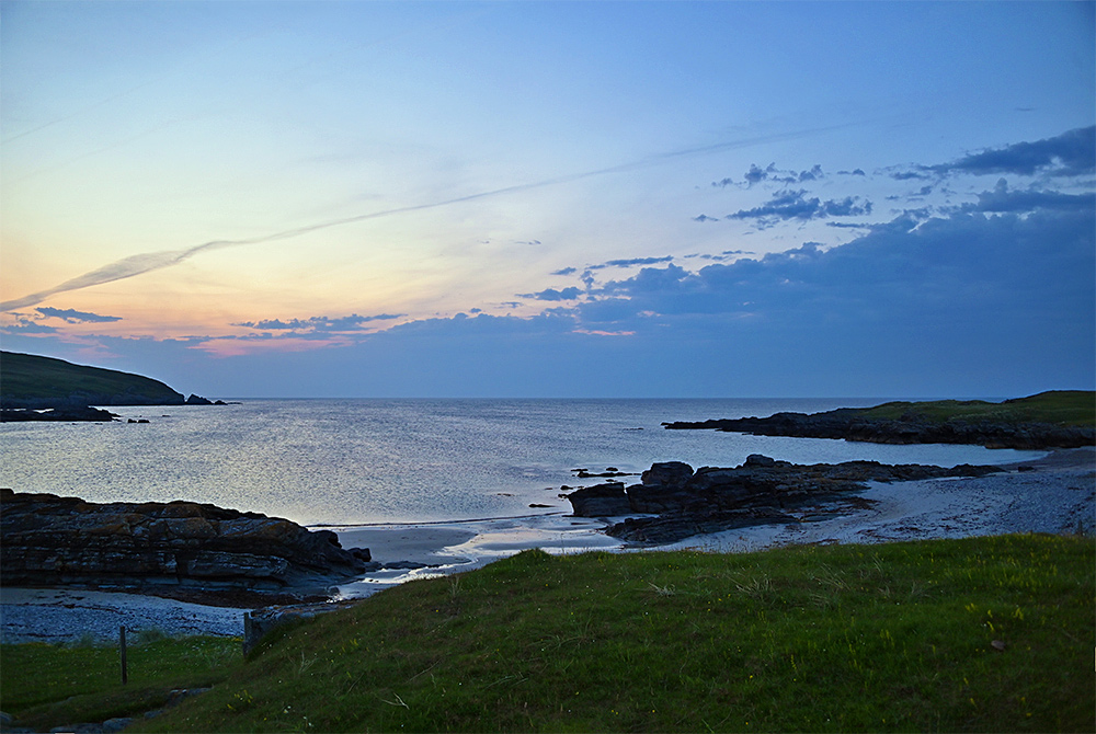 Picture of a summer evening gloaming over a bay with cliffs, beach and rocks