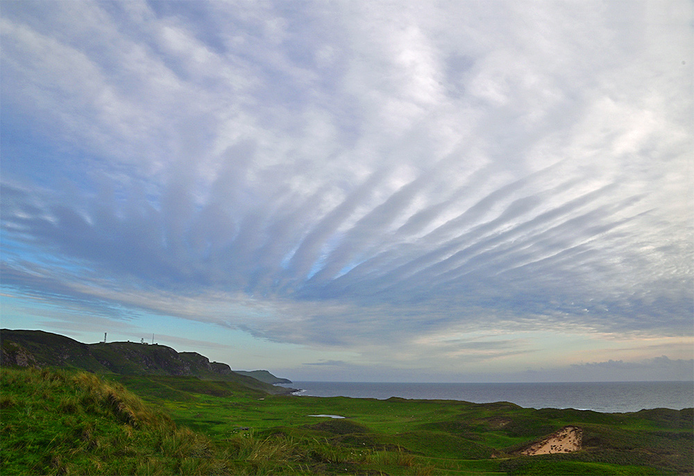 Picture of some clouds in a stripe formation over a coastal landscape