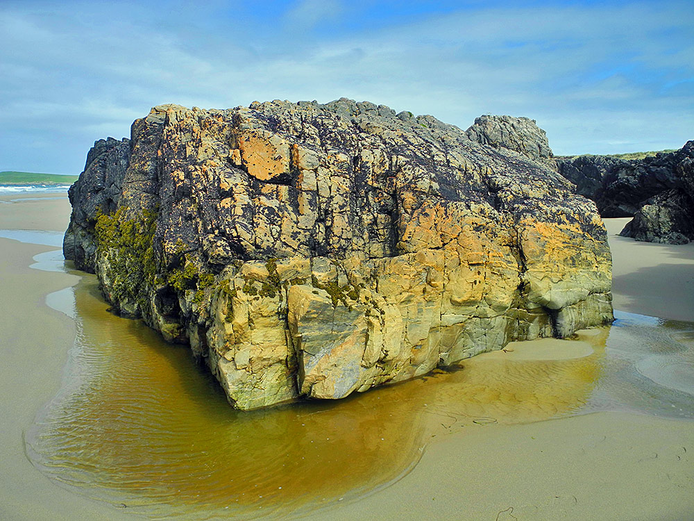 Picture of a very large piece of rock on a sandy beach