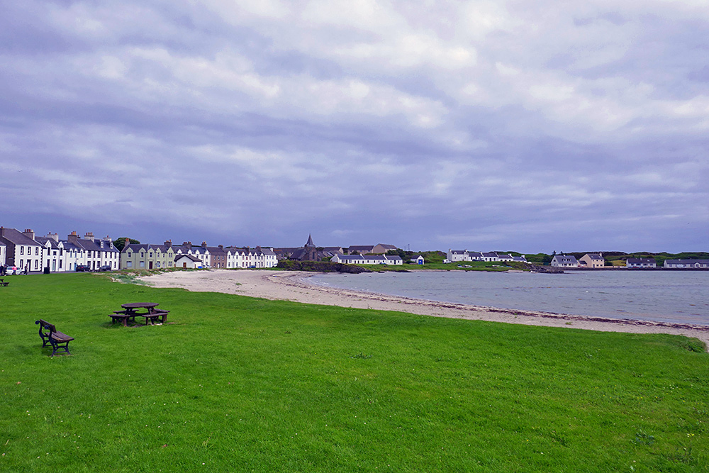Picture of a coastal village around a bay with a sandy beach on a cloudy June afternoon