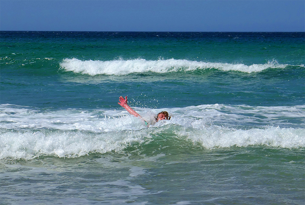 Picture of a person swimming in some waves off a beach
