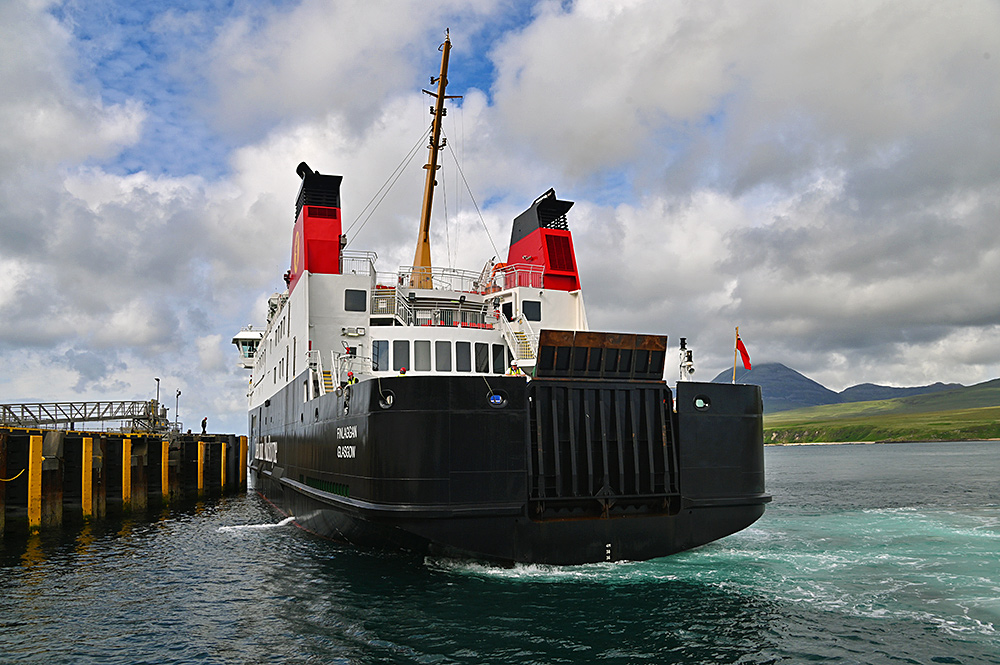 Picture of the Calmac ferry MV Finlaggan berthing at a pier in a sound between two islands