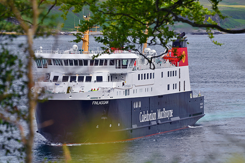 Picture of the Calmac ferry MV Finlaggan seen through some trees from a high vantage point