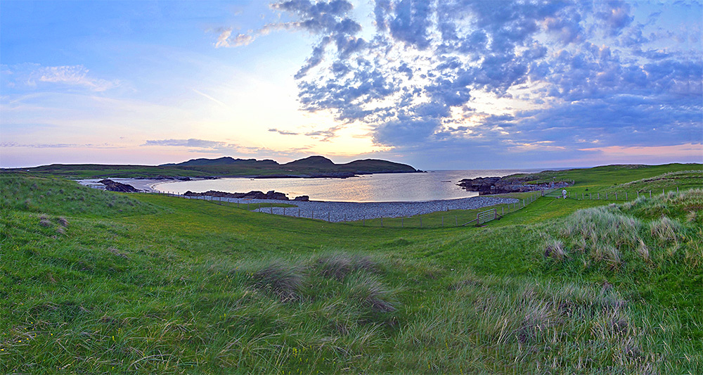 Panoramic picture of a small bay with a beach bordered by some rocky shores on a June late evening