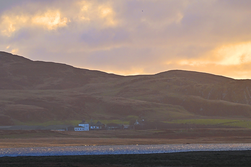 Picture of a small farm distillery in mild November afternoon light, seen across a freshwater loch