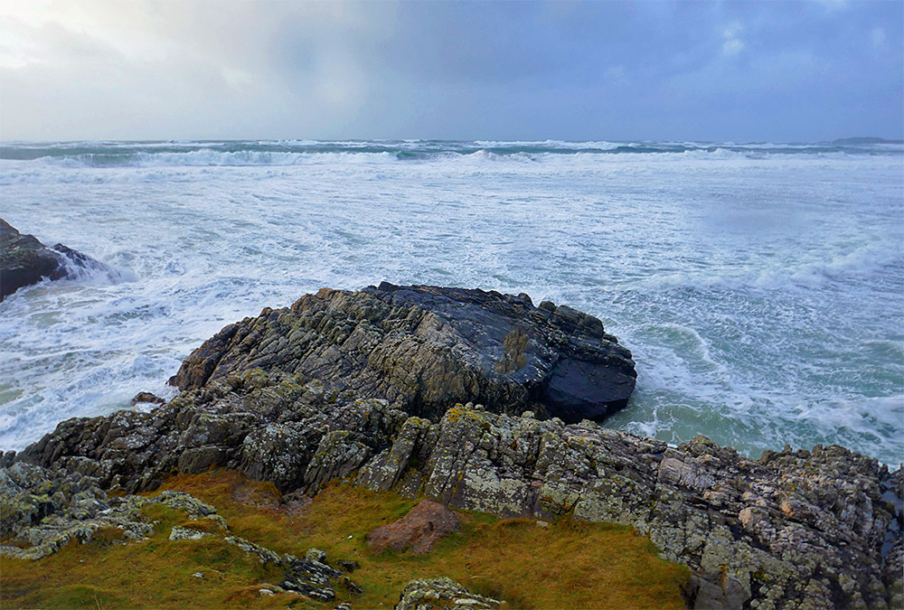 Picture of breaking waves leaving white foam at a rocky shore