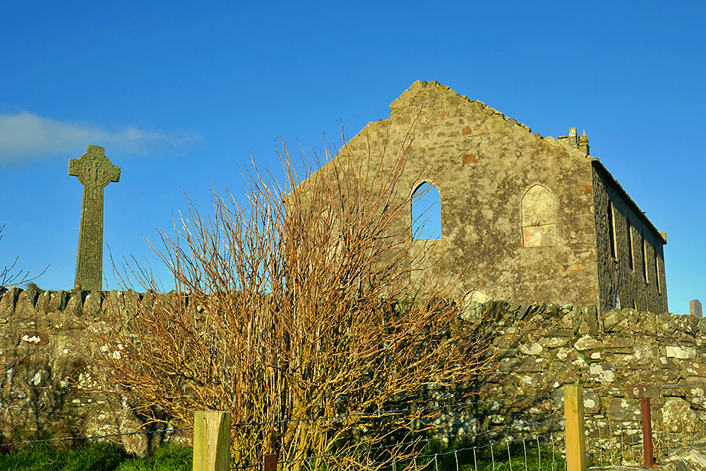 Picture of the ruin of a church, a Celtic cross next to it