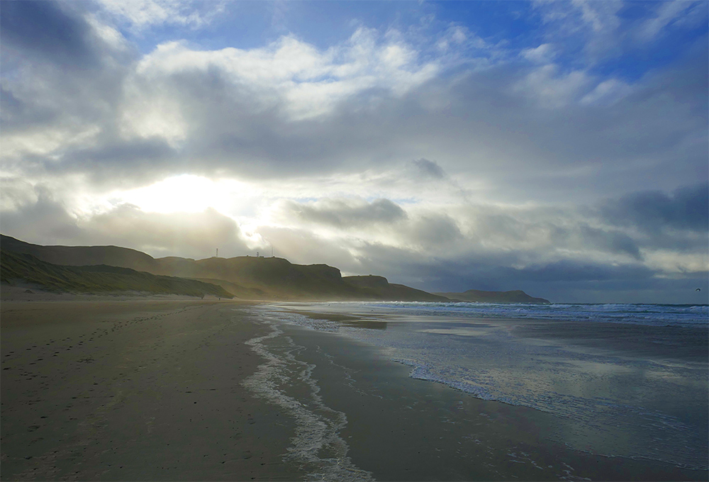 Picture of a view down a beach on a November morning, the sun just breaking through the clouds