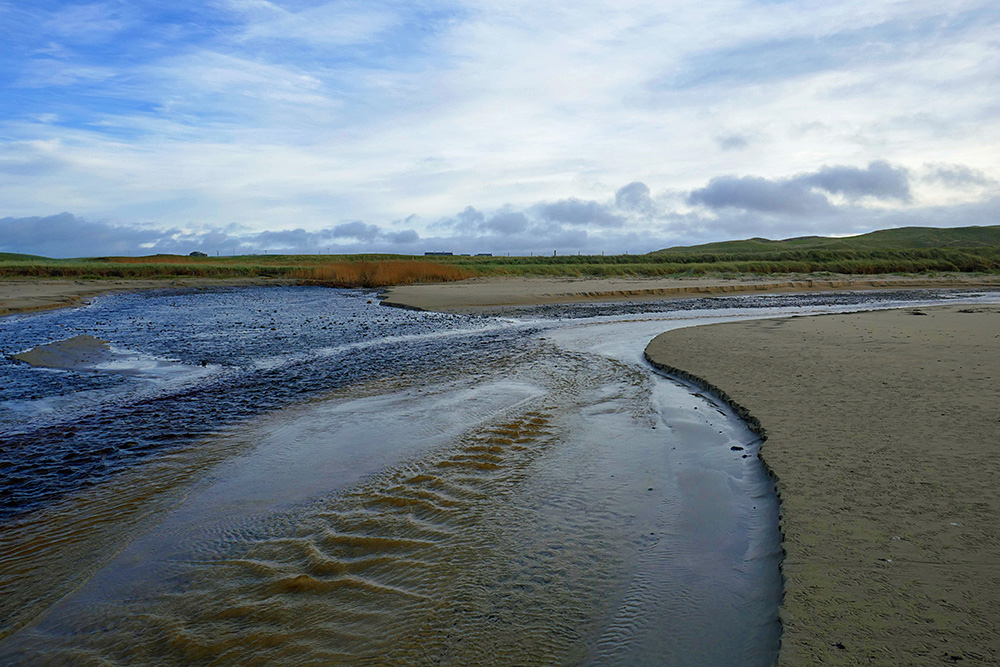 Picture of two burns (streams) flowing on to a beach where they join before flowing into the sea