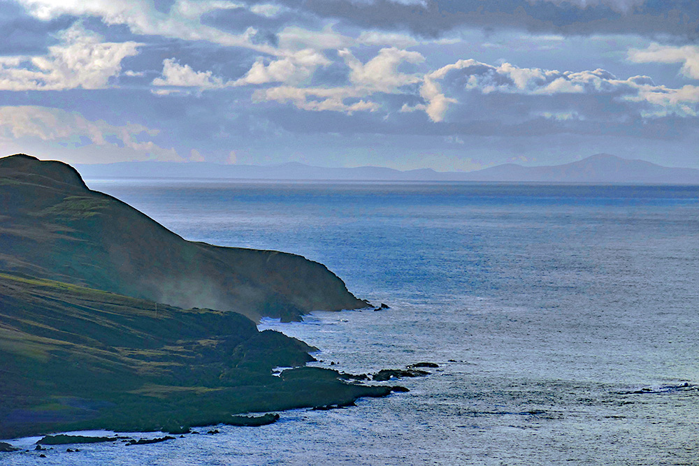 Picture of a view across a channel to a distant shore, a rugged coastline in the foreground