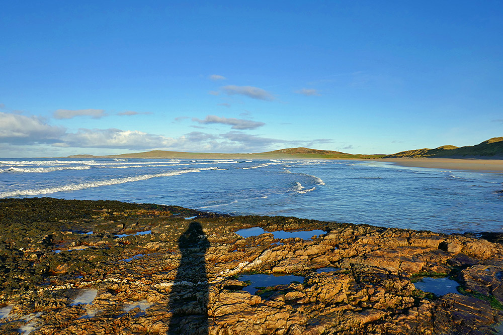 Picture of a view over a wide sandy beach from a rocky outcrop on the beach