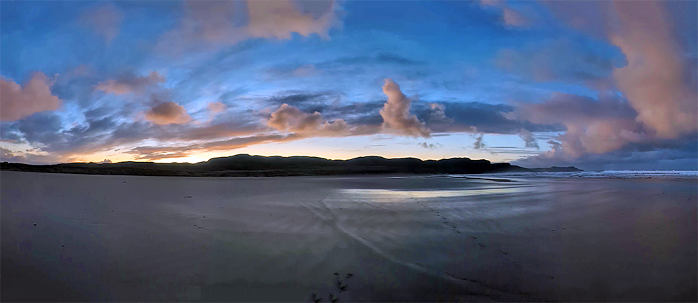 Panoramic picture of dramatic clouds at dawn over a wide sandy beach