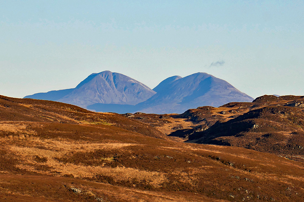 Picture of three mountains seen across a rugged hilly landscape