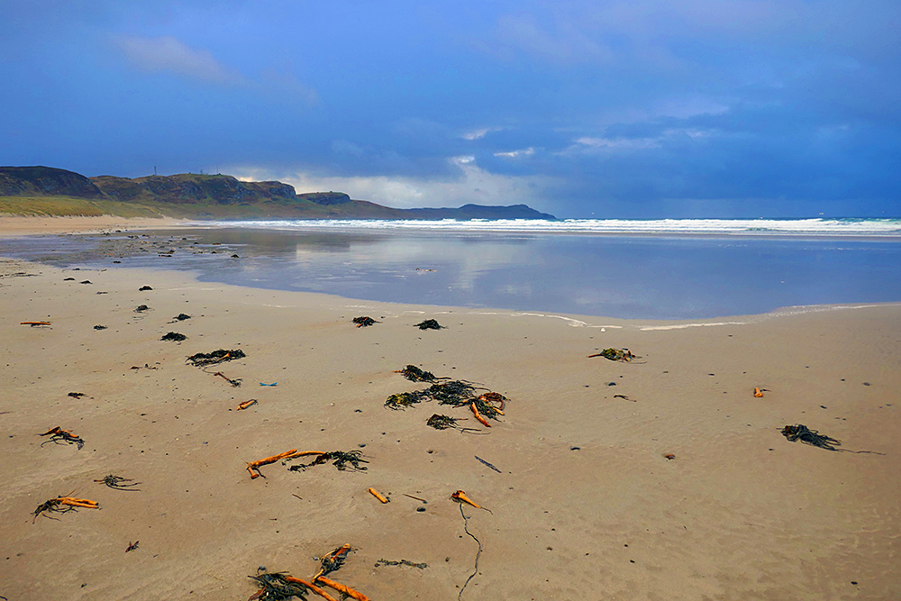 Picture of a wide sandy beach with the run off of a wave covering a large part of it