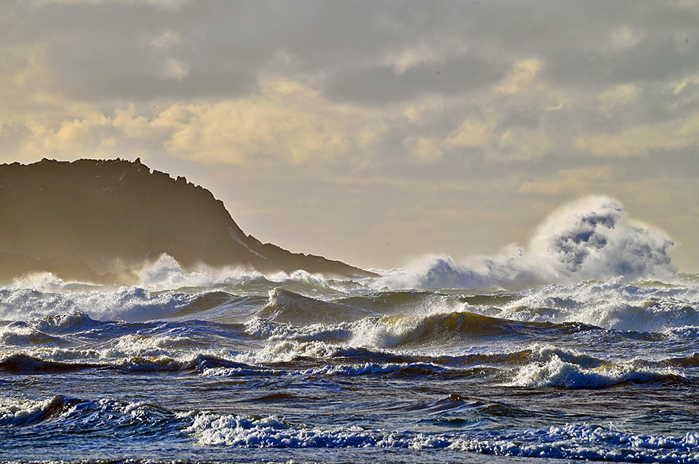 Picture of breaking waves in front of a rugged rocky shore