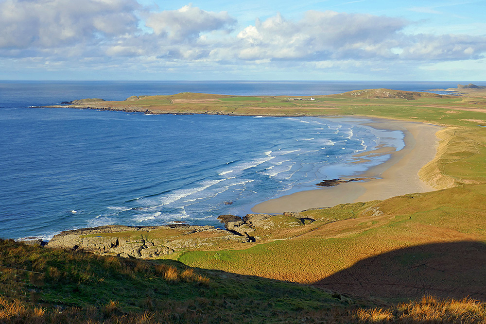 Picture of a view over a wide bay with a sandy beach from a high vantage point
