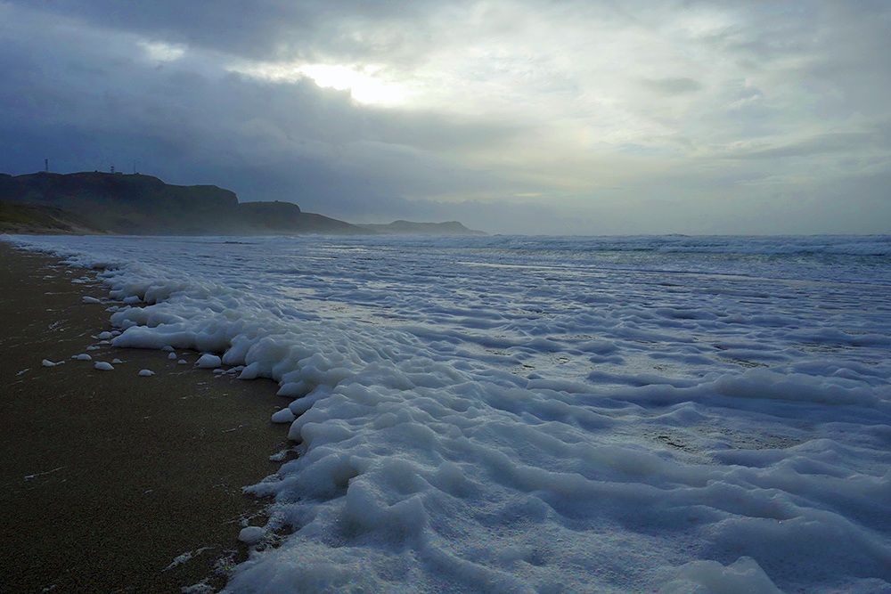 Picture of a beach covered in sea foam during a November storm