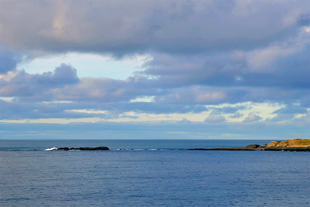 Picture of a small rocky island outcrop at the end of a wide bay