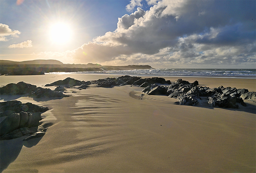 Picture of rocks on a sandy beach forming what vaguely resembles a circle