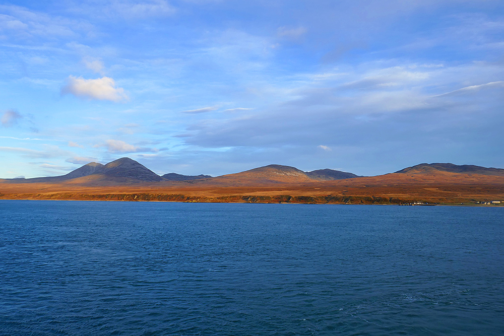 Picture of a view across a sound between two island to a hilly rural landscape