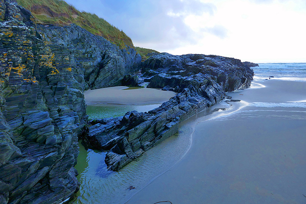 Picture of a rocky hillside at the end of a sandy beach