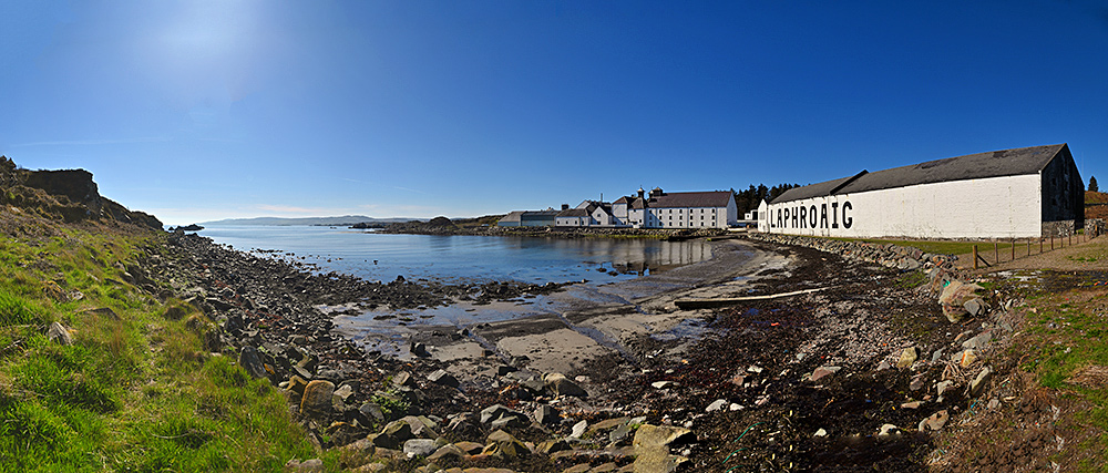 Panoramic picture of a sea loch with a coastal distillery (Laphroaig) on the shore on a beautiful sunny day
