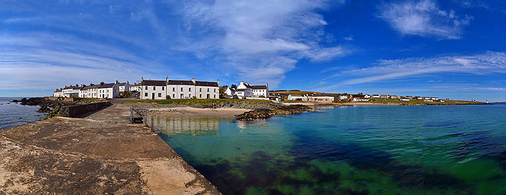 Panoramic picture of a coastal village seen from its small pier on a mostly sunny April day